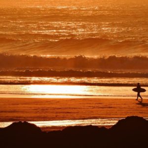 Perranporth beach surfing - sunset with surfer walking on beach