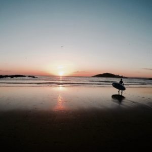 Surfer walking into the sunset at Bantham beach