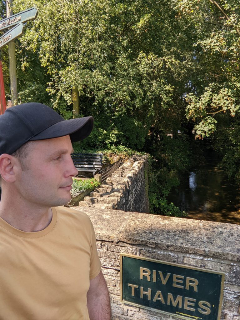 Tom looking sideways at the River Thames sign in Cricklade