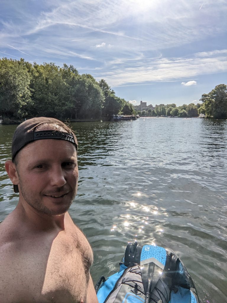 Tom standing on the paddle board on the thames with Windsor Castle in the background