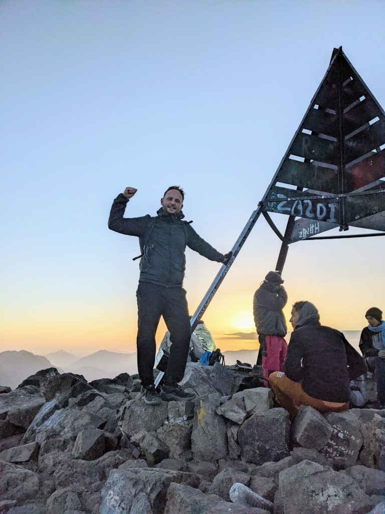 Tom standing at the top of mount toubkal after climbing mount toubkal