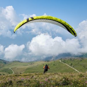 Paraglider flying over hills with valley in background