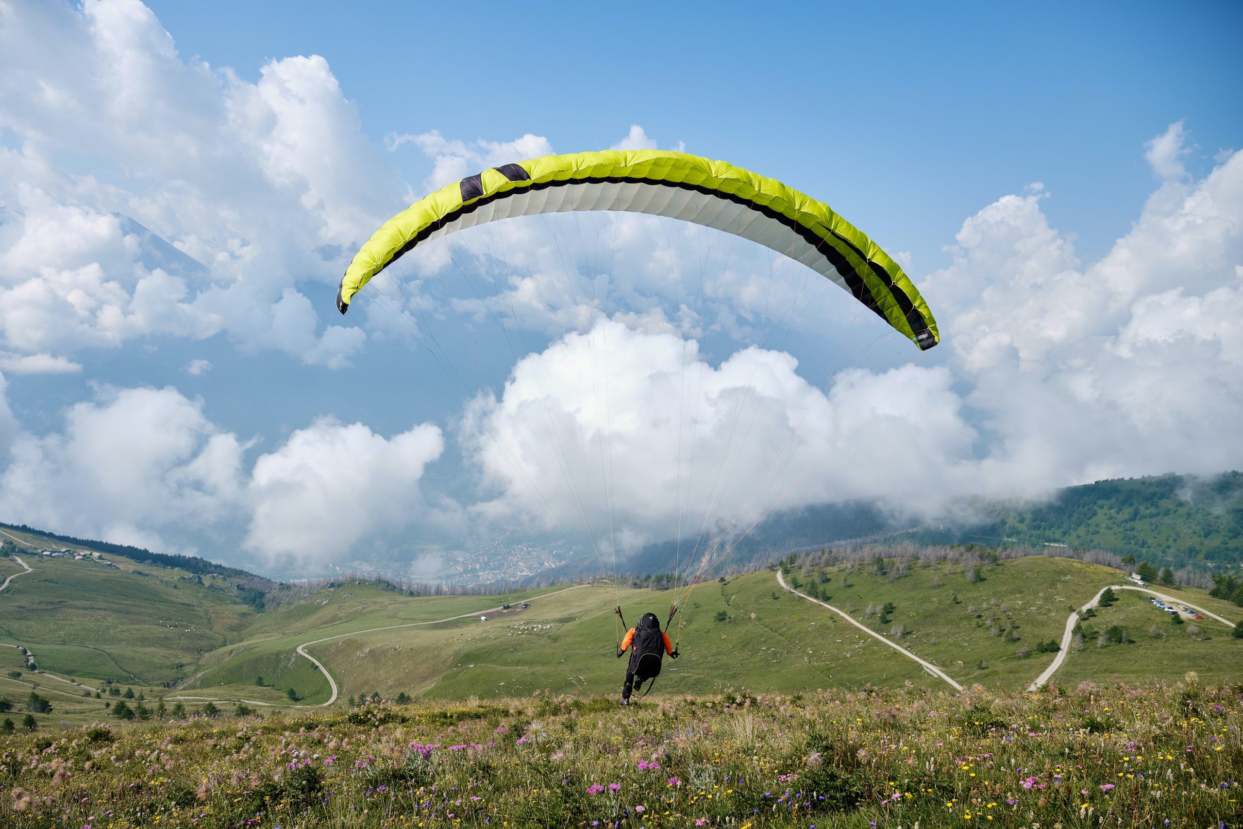 Paraglider flying over hills with valley in background